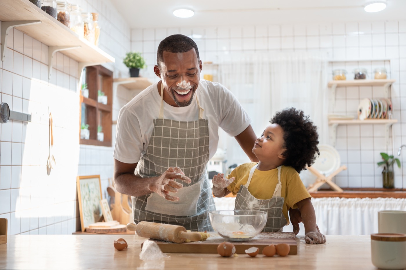 Parent and child laughing while baking together in the kitchen
